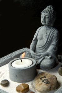 kleiner Buddha mit Sand auf dem Weg zum Glück mit Buddhas Weg